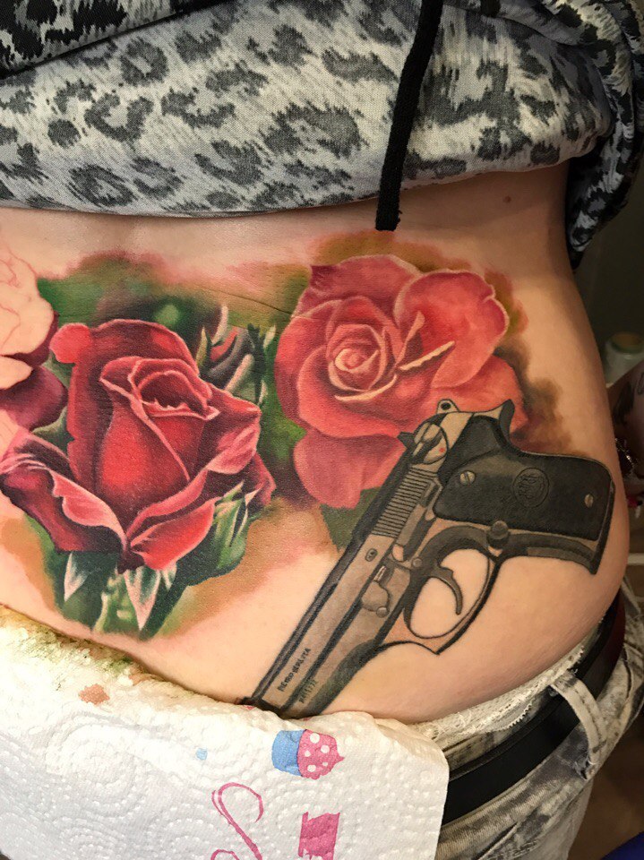 У девушки на теле тату розы с пистолетом